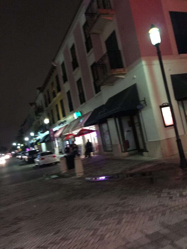 A quiet city street lined with storefronts and streetlights at night.