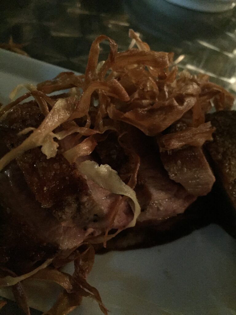 A plated dish topped with crisp onions, photographed close up.