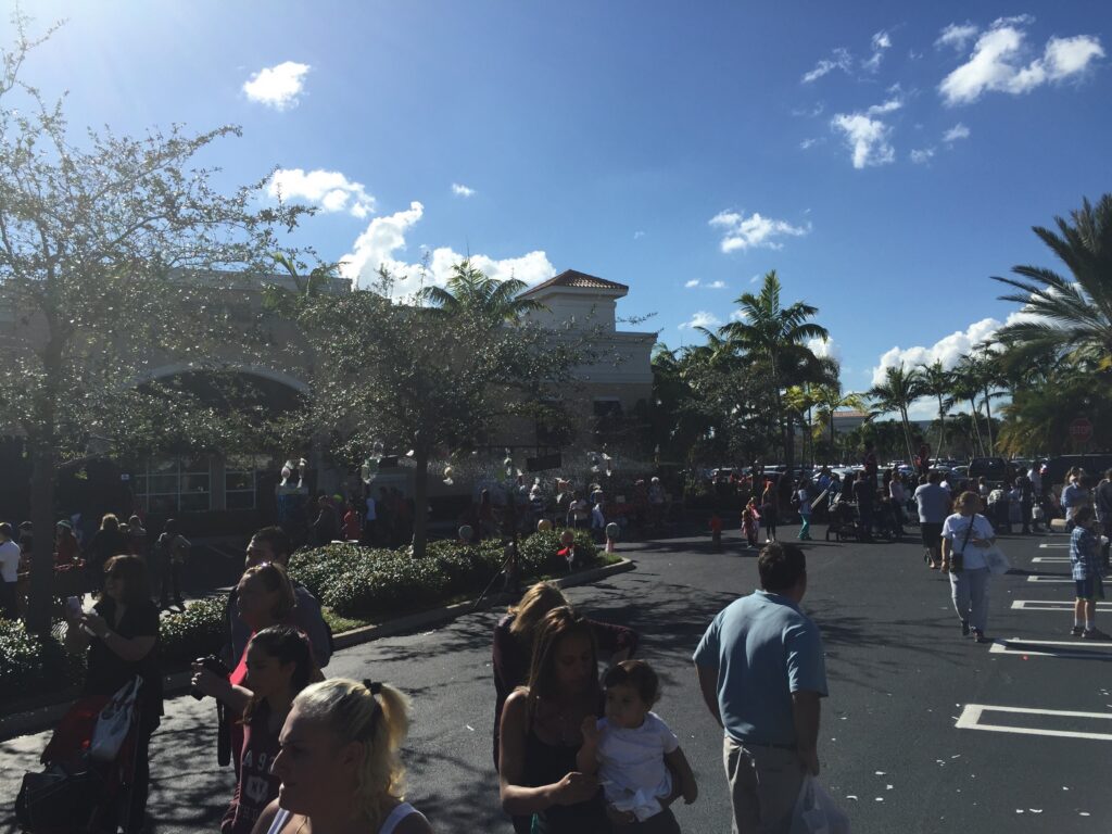 A busy Disney walkway beneath a bright blue sky.