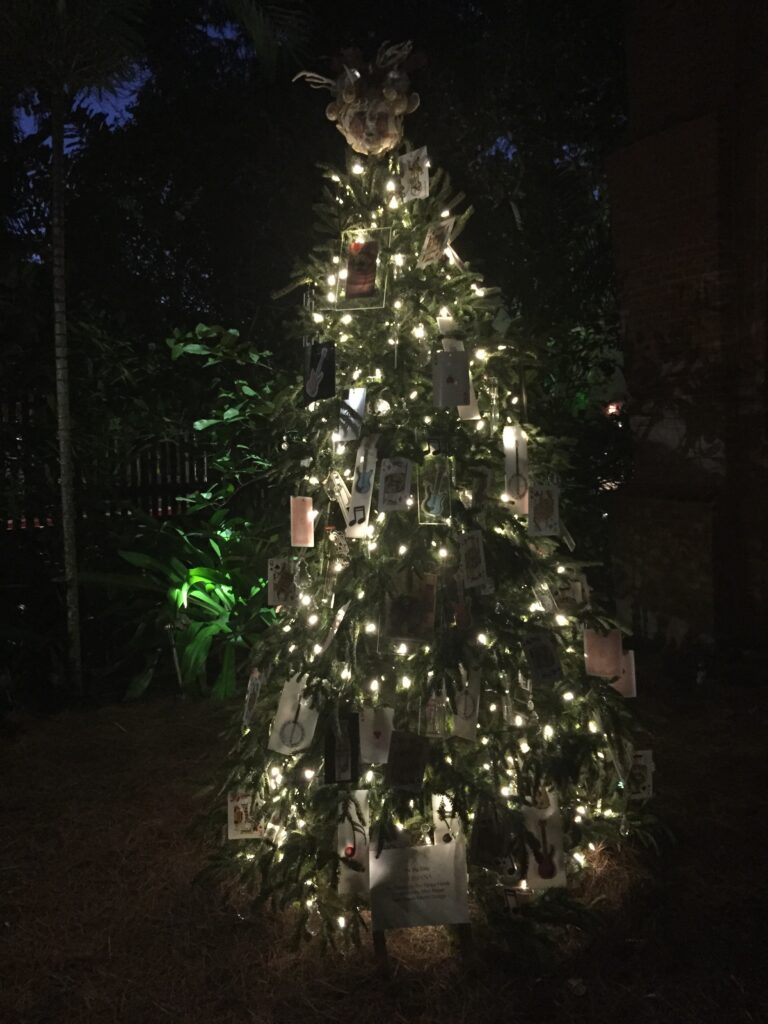 A silver-and-white decorated Christmas tree glowing outdoors at night.