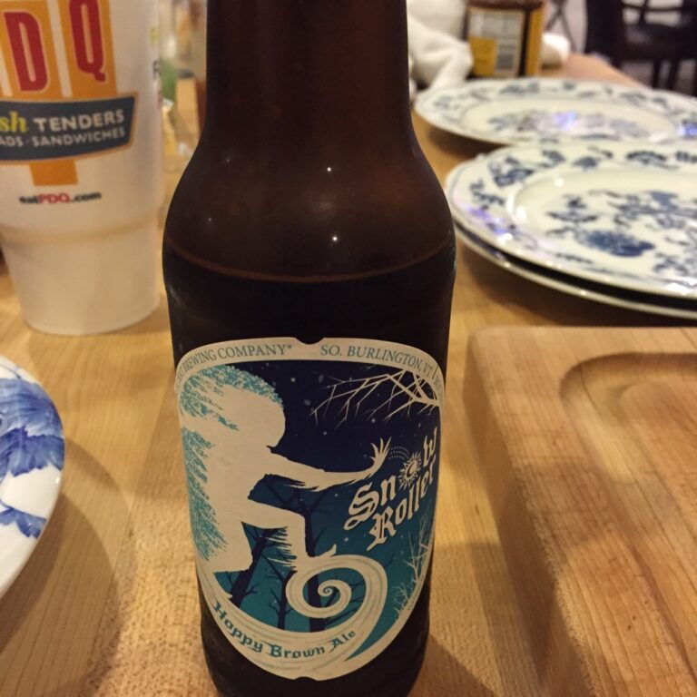 Craft beer bottle on a table beside a drink.