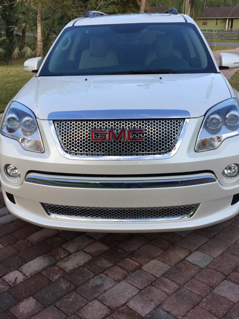 Front view of a white GMC SUV parked on a brick driveway.