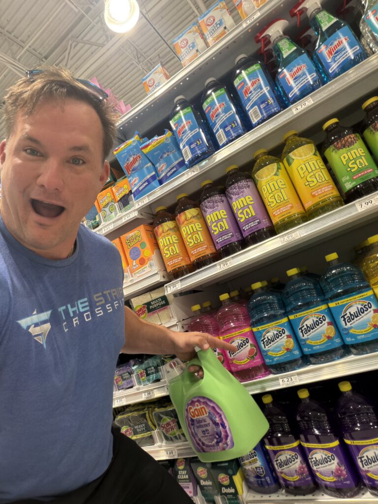 Robert W. Kuypers taking a playful selfie in a store cleaning aisle while holding a green bottle of cleaner.