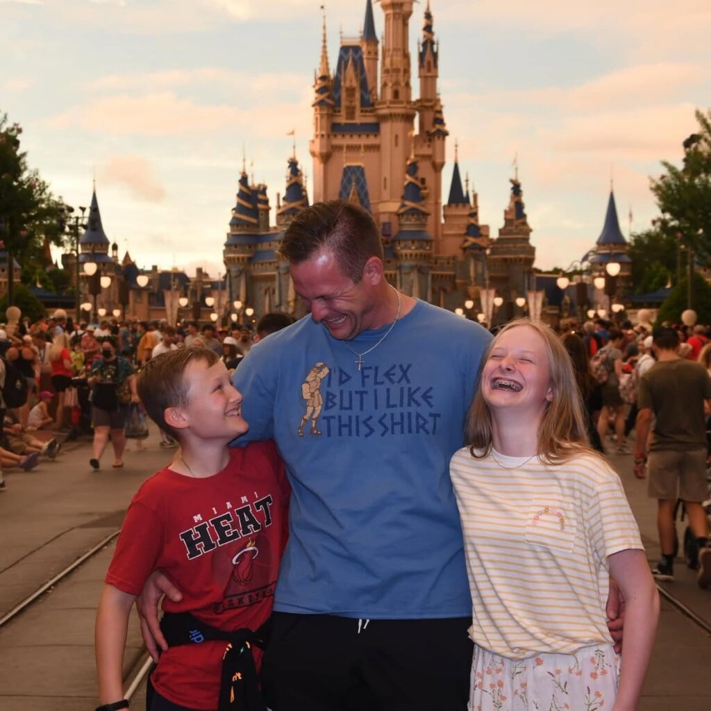 Robert W. Kuypers laughing with Braden and Kenley in front of Cinderella Castle at Disney.