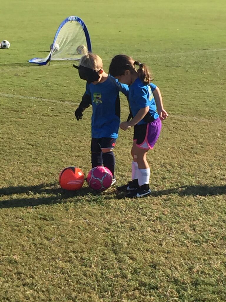 Children playing soccer on a grassy field.