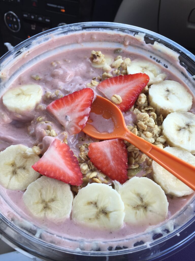 Bowl of fruit topped with banana and strawberry slices.