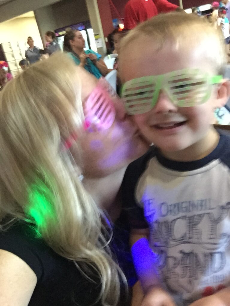 Two children wearing colorful party glasses and glow accessories.