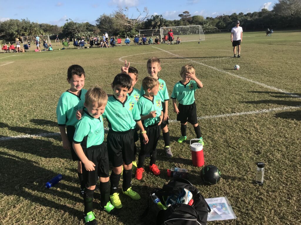 Youth soccer team posing beside a playing field.