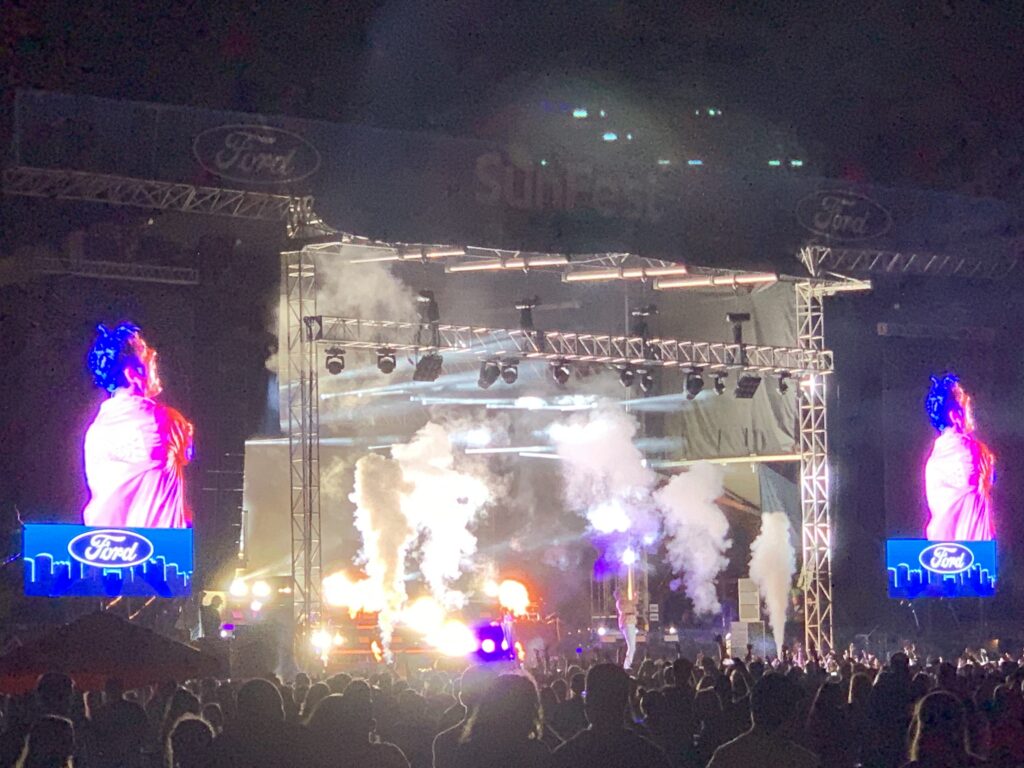 A concert stage glowing with lights in a crowded arena.