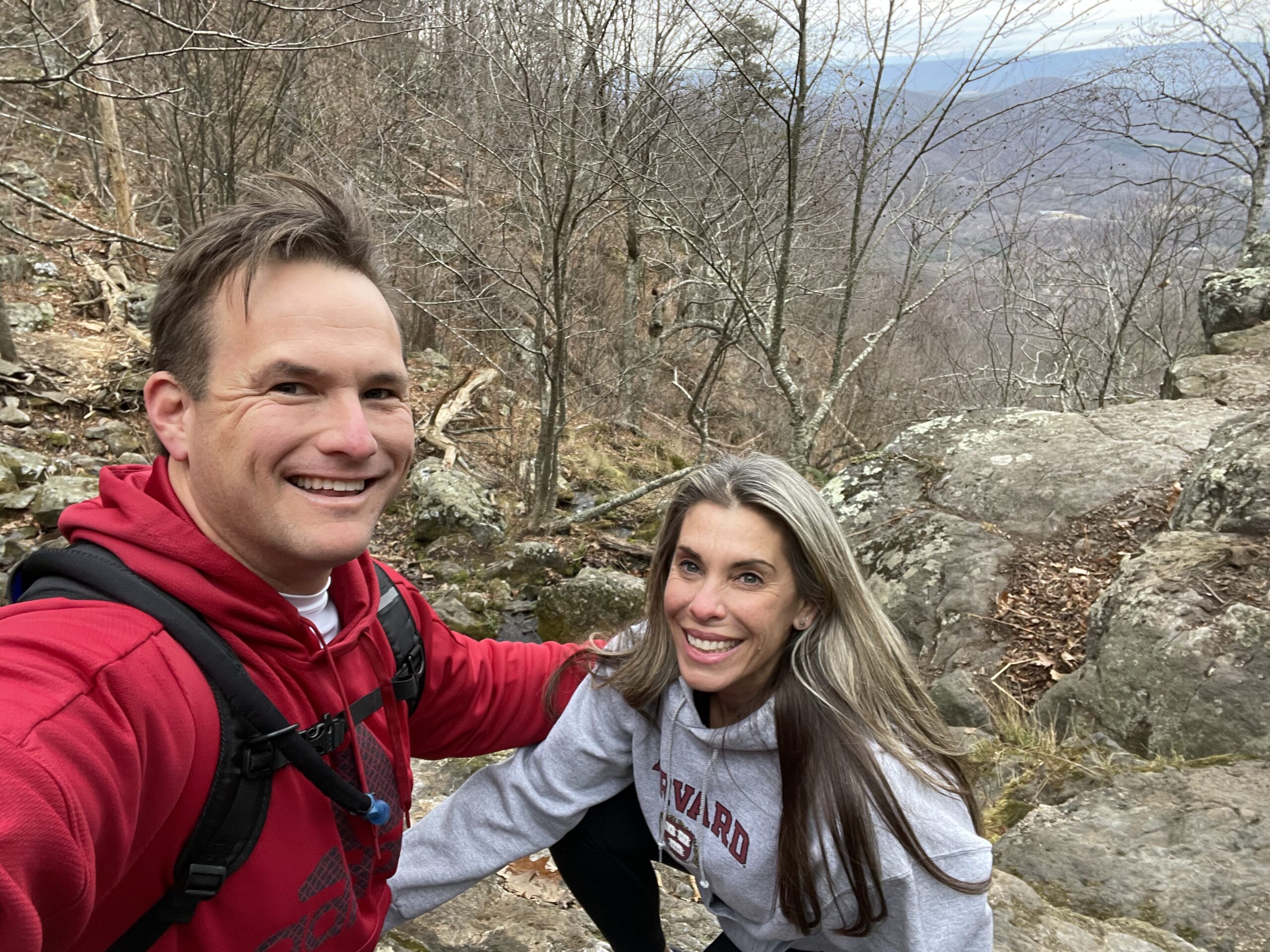 Two hikers taking a break on a rocky wooded trail.