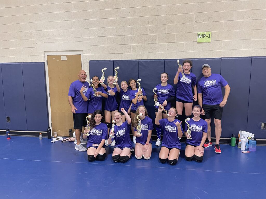 Youth team and coaches posing in a gym.