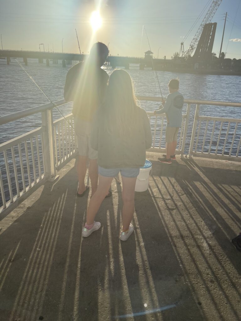 Visitor standing on a waterfront pier in the sunlight.