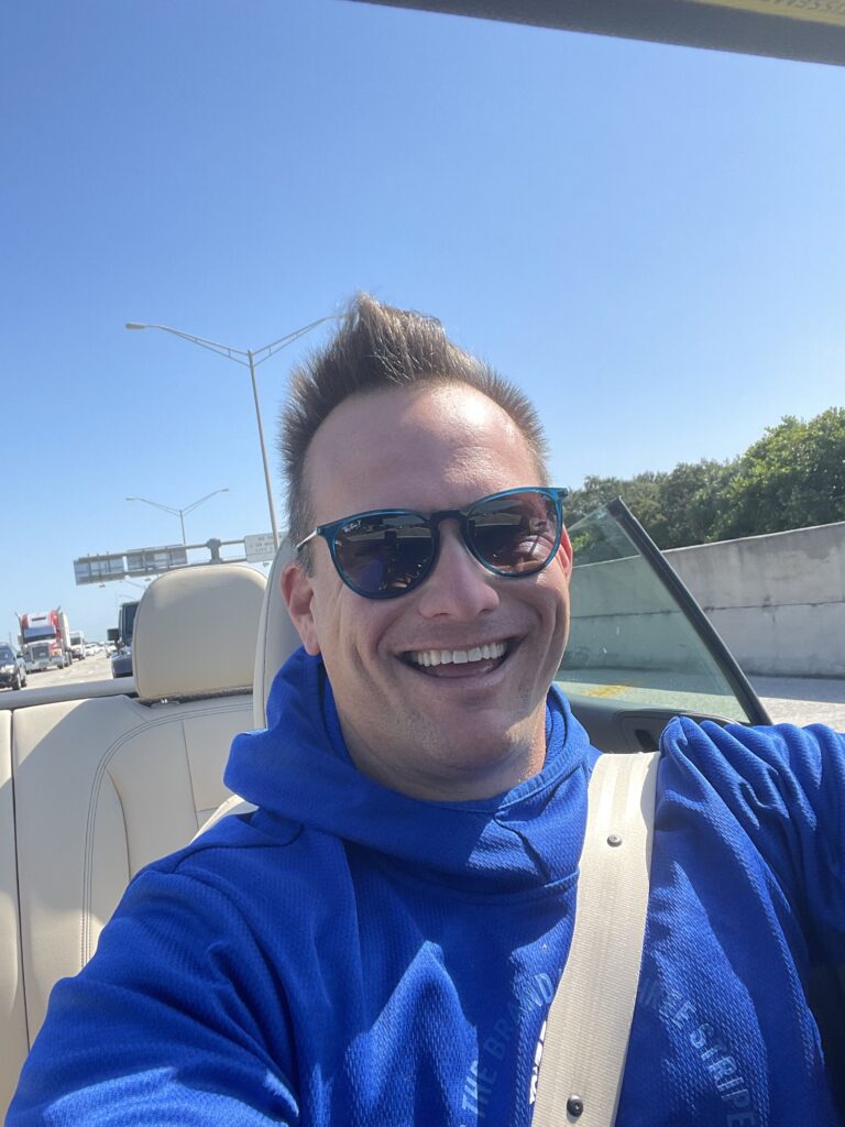 Man wearing sunglasses smiling aboard a boat.