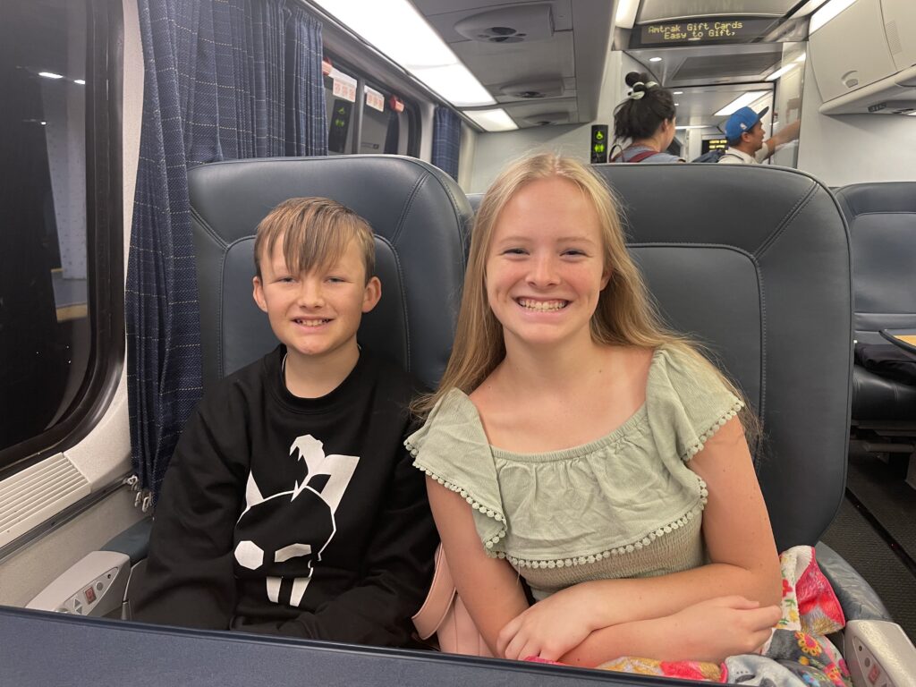 Two children smiling from their train seats.