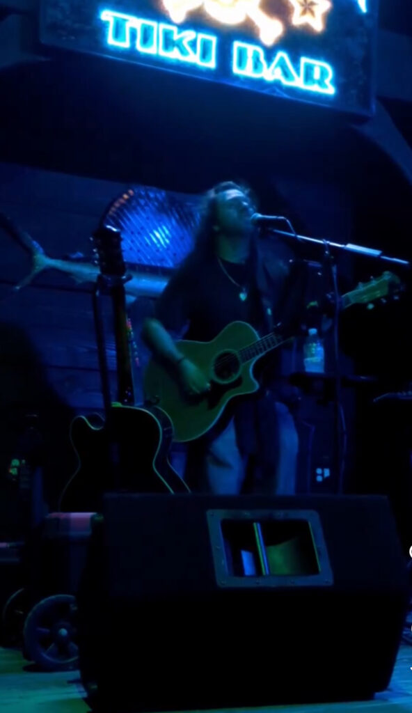 Musician performing under blue stage lights.