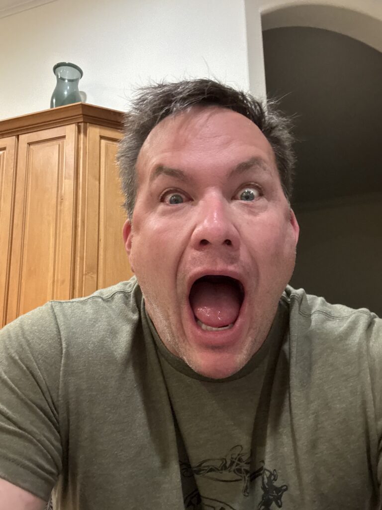 Man making a playful expression in a kitchen.