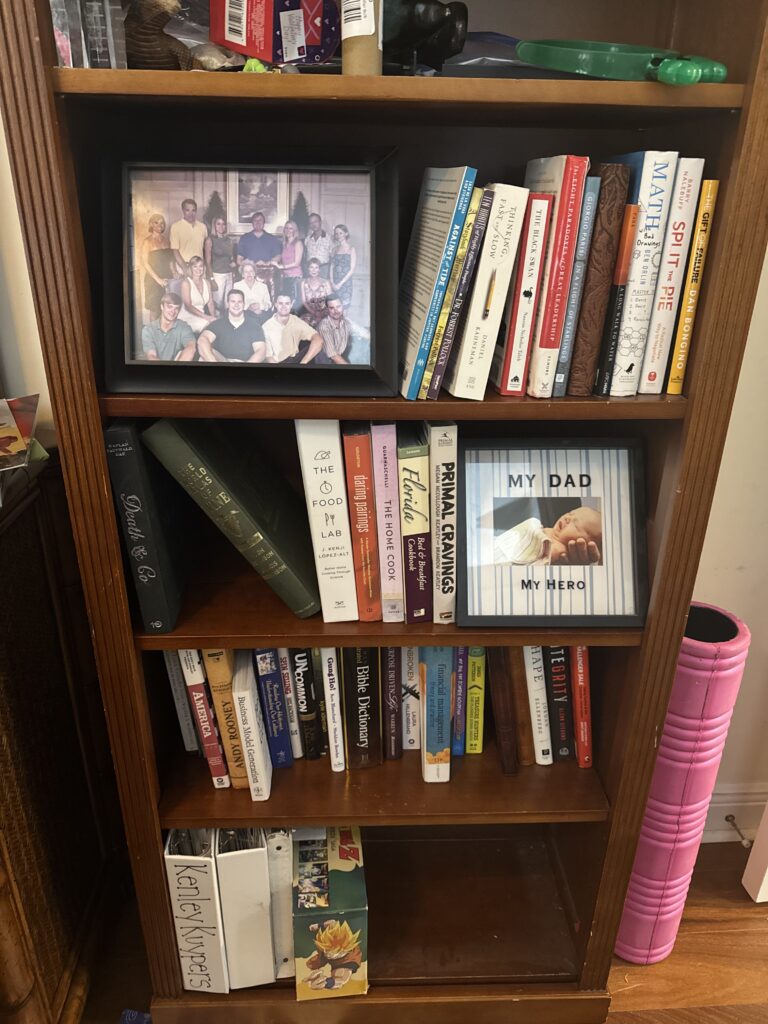 Books and framed family photographs on a shelf.