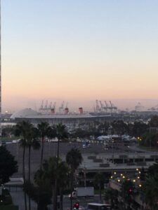 A distant harbor and cranes beneath a pale evening sky.
