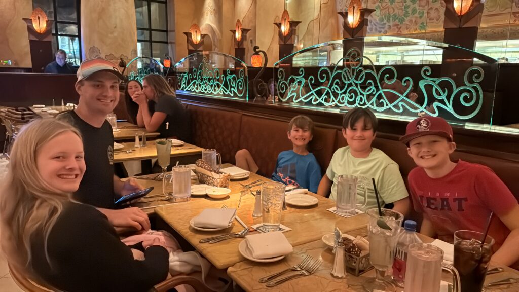 The kids smiling together around a restaurant table.