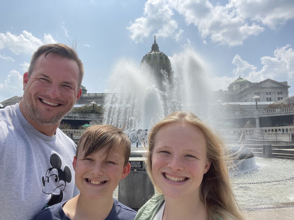 Robert W. Kuypers with Kenley and Braden in front of a fountain and capitol building.