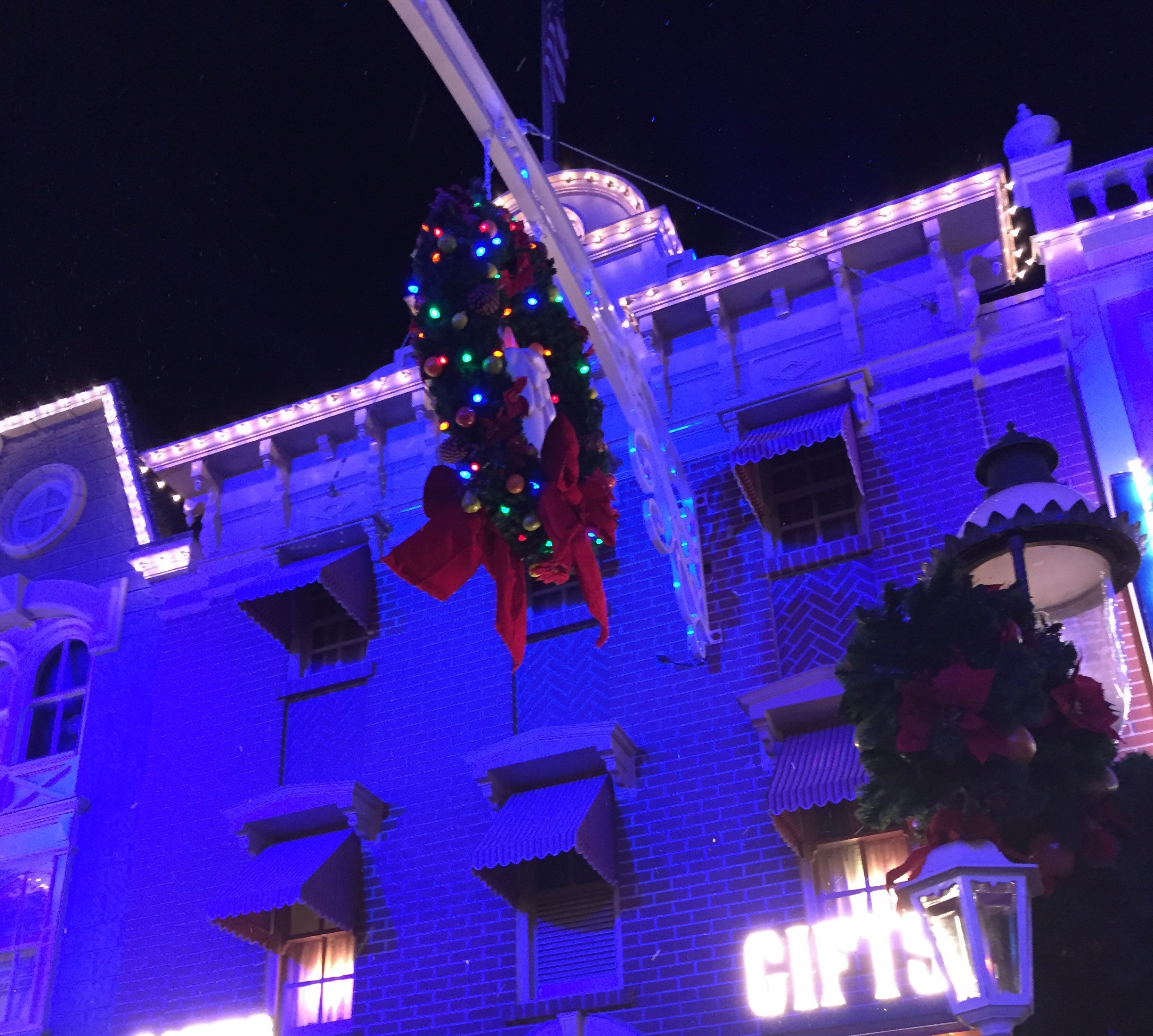 City Hall facade glowing blue and purple with oversized holiday wreaths.