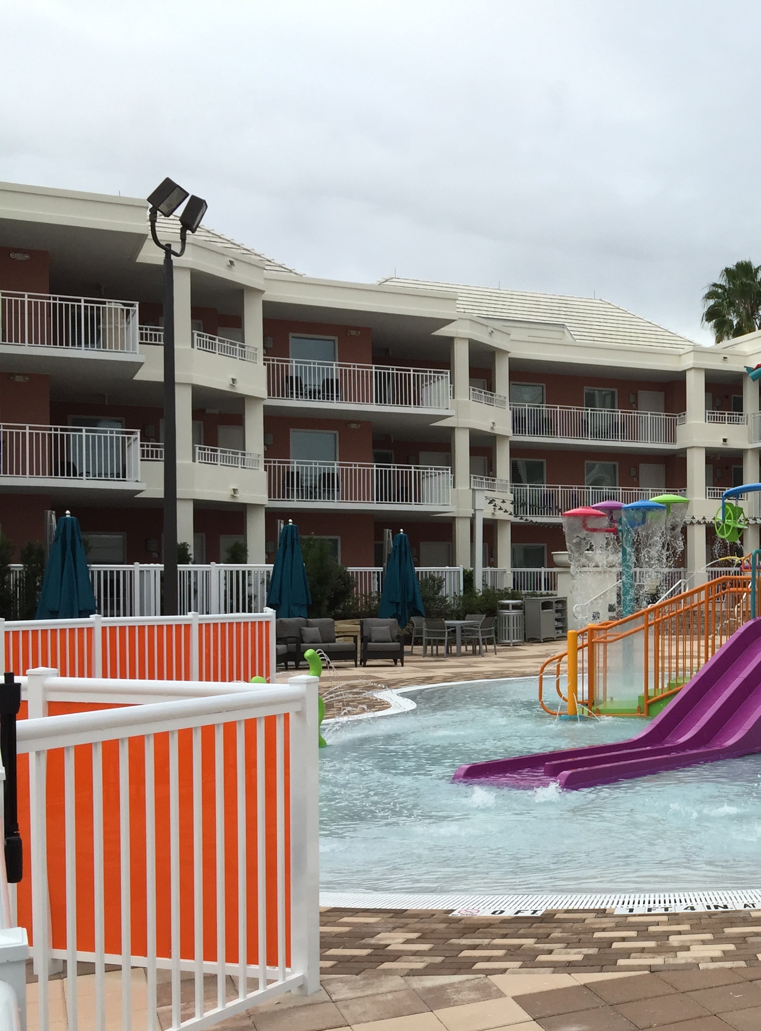 Colorful splash-pad slides and fountains in a hotel courtyard.