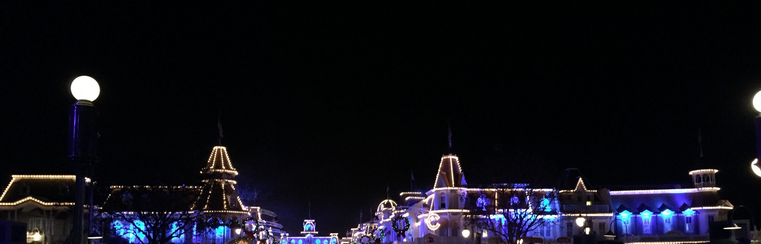 Blue and white lights outlining Main Street buildings beneath a dark sky.