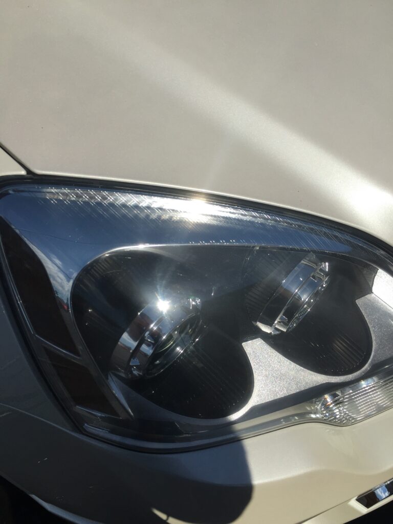 Close-up of a car headlight in bright sunlight.