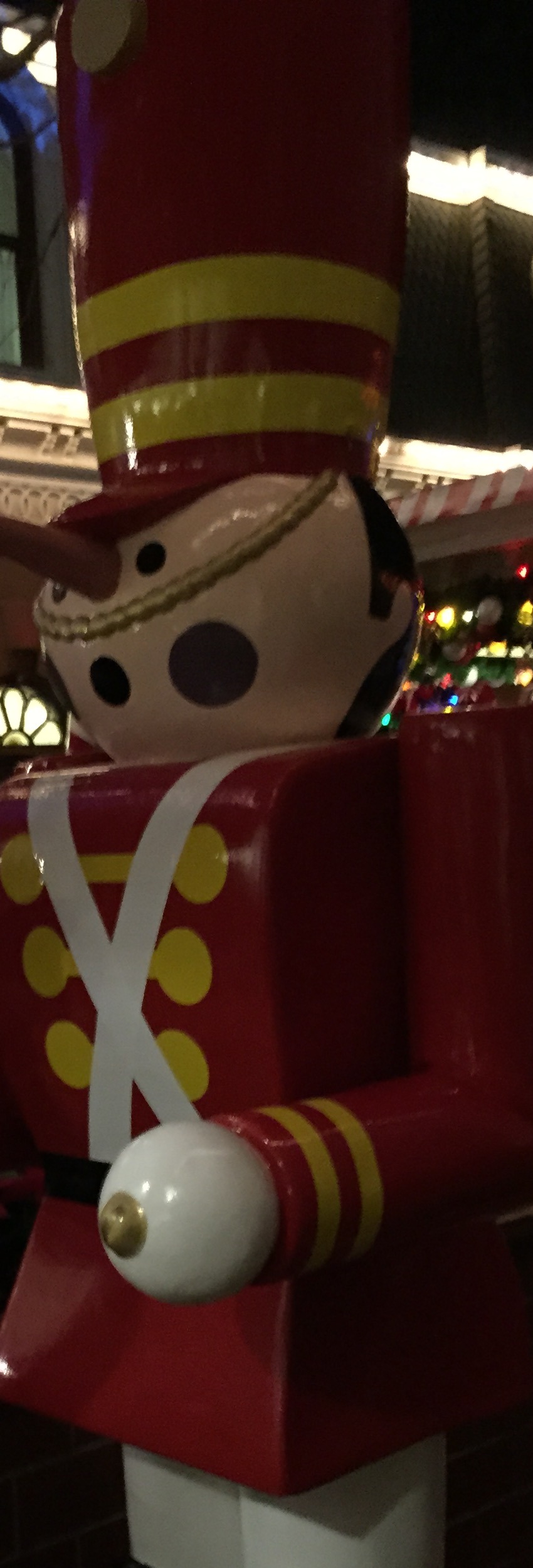 Red toy soldier decoration glowing under holiday lights after midnight at Disney.
