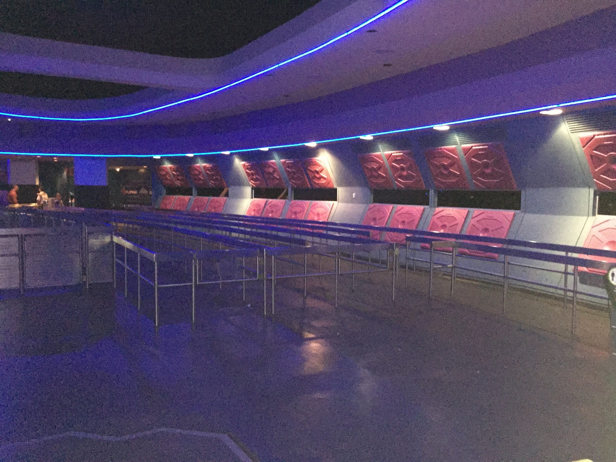 An empty futuristic queue area illuminated by blue lines.