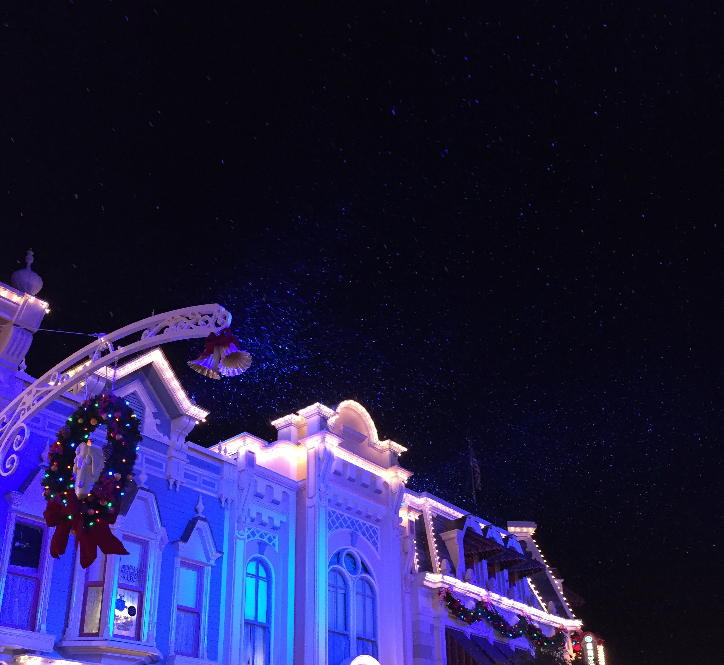 Main Street Confectionery decorated with wreaths beneath drifting artificial snow.