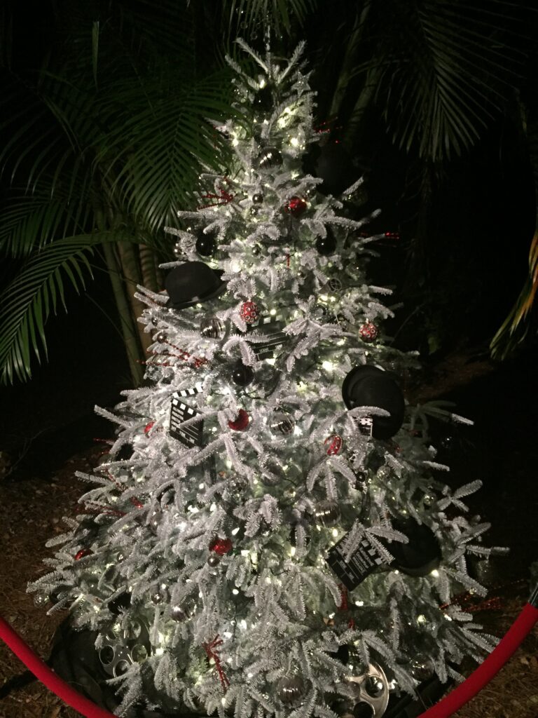 A silver holiday tree glowing outdoors at night.