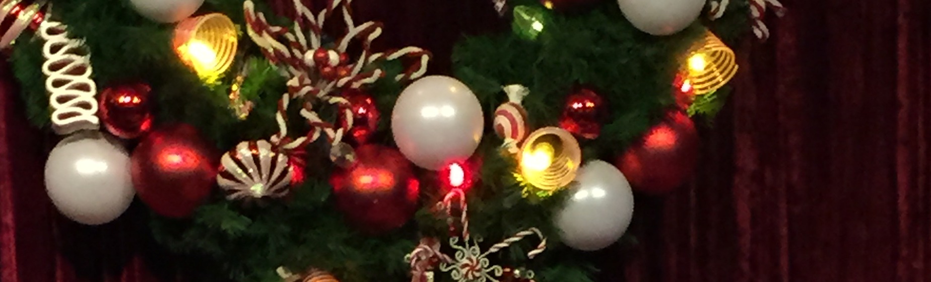 Red, white, and gold holiday wreath glowing against red velvet at Disney.
